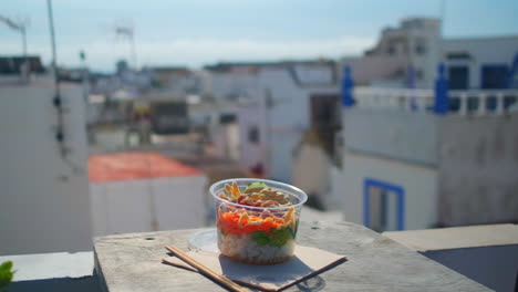 Close-up-track-shot-of-tasty-and-healthy-Poke-Bowl-served-outdoors-on-balcony-with-beautiful-city-view-in-summer