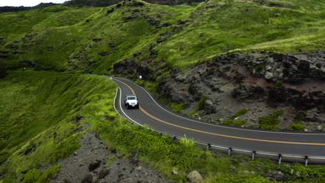 aerial tracking view of jeep driving around cliffs, hawaii.