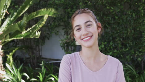 feliz mujer caucásica de pie y sonriendo en el jardín soleado, cámara lenta