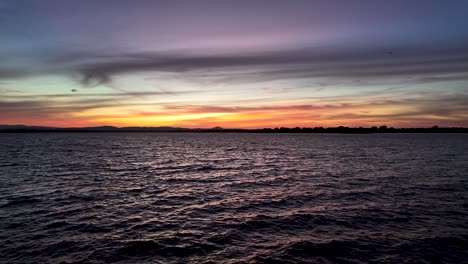 the setting sun is casting an orange glow on the water, creating a beautiful and dramatic scene