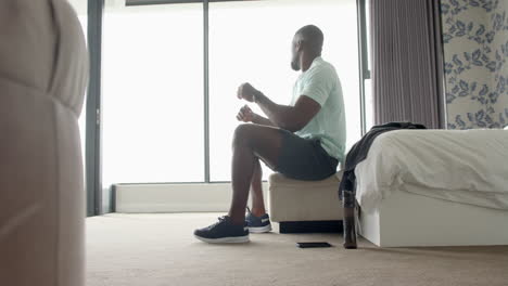 sitting on bed, man relaxing in bedroom with water bottle and smartphone nearby