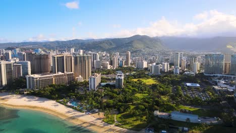 metropolitan city on the beach of a tropical island with mountain range in background during sunrise