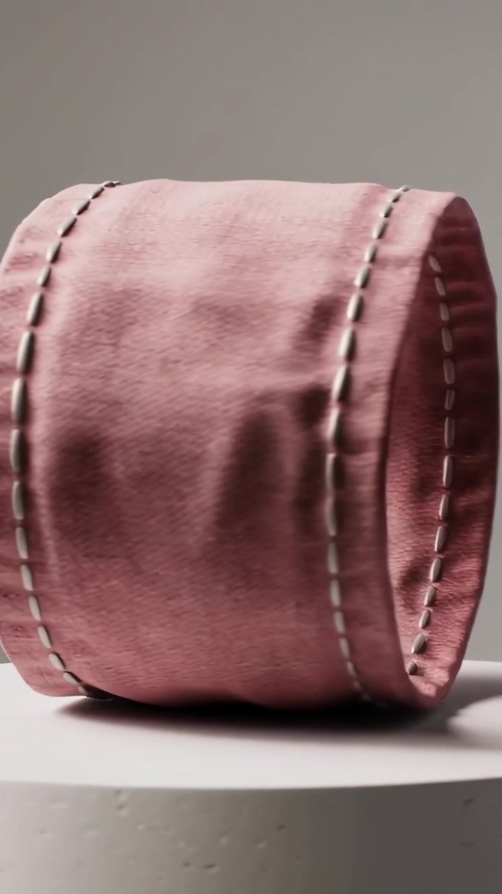 Vertical video: Rotating pink fabric ring from side to upright on pedestal in studio