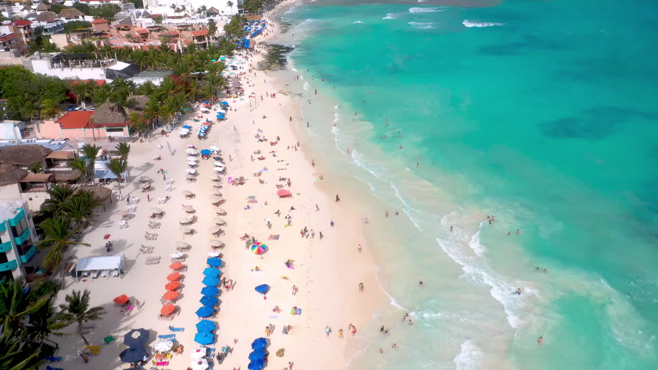 Toma de dron de la costa y los resorts de Playa del Carmen con gente en la playa.