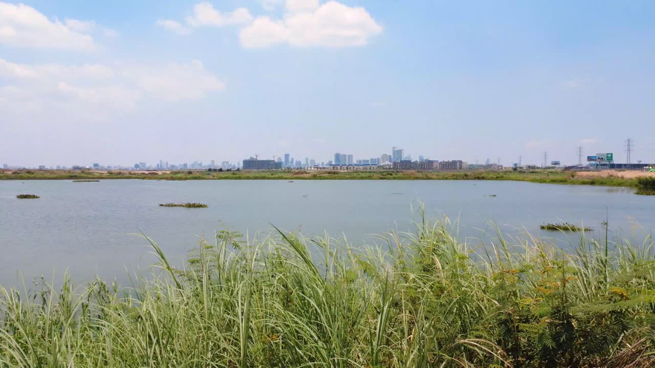 Phnom Penh city view at distant from the lake near Hun Sen Blvrd, Gimbal tracking shot