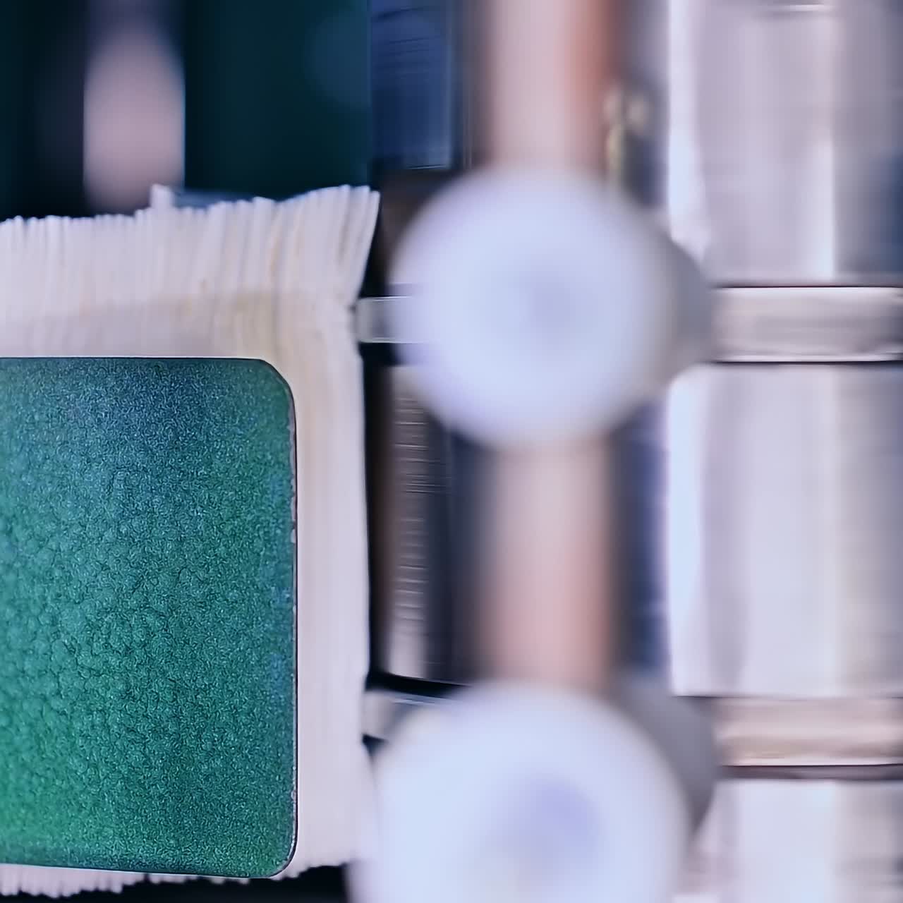 Big metal roller twisting and pushing the non-woven cloth into conveyor. Production line of diapers at the factory close up