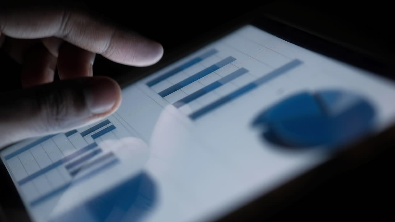 mano tocando una pantalla de tableta con gráficos y gráficos