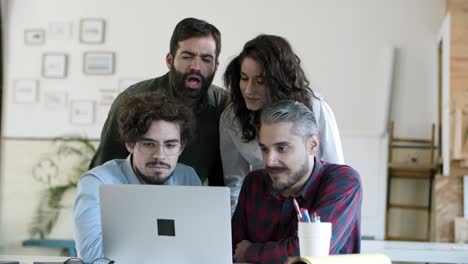 smiling coworkers talking via laptop in cozy office