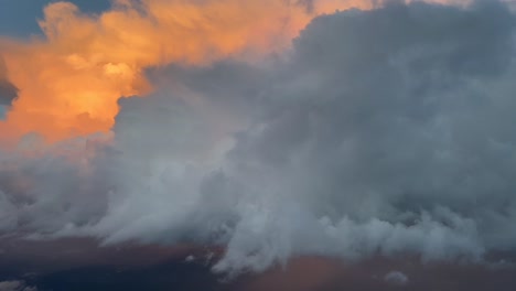 vista aérea desde la cabina de un jet de un enorme cumulonimbus iluminado con color naranja en la tarde a las 35