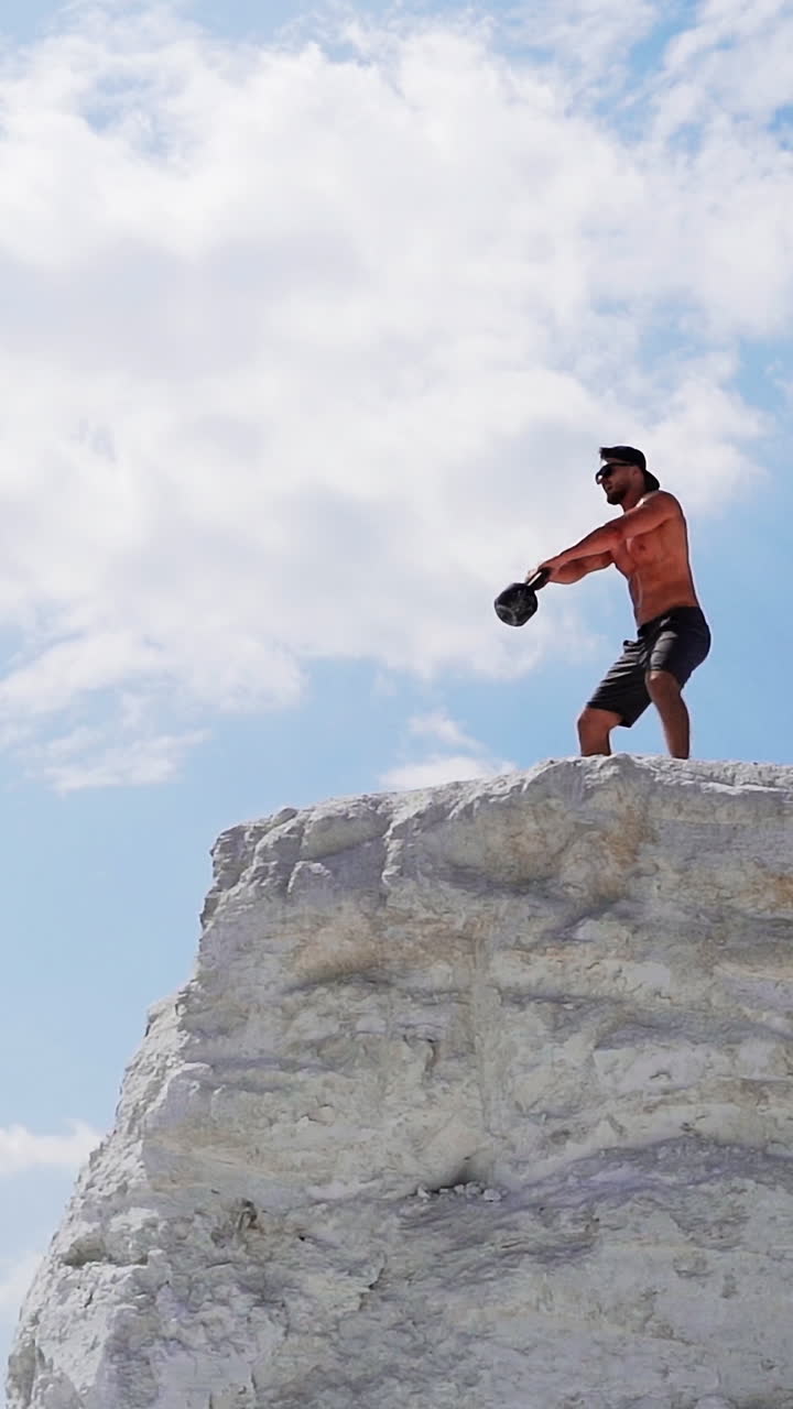 Sportive man with dumbbell. Athletic man doing workout routine on nature Vertical video