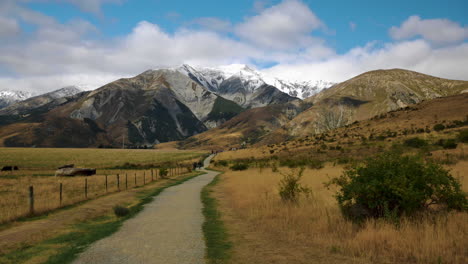 ruta de senderismo rural rodeada de hermosos paisajes y picos nevados de montaña en el fondo