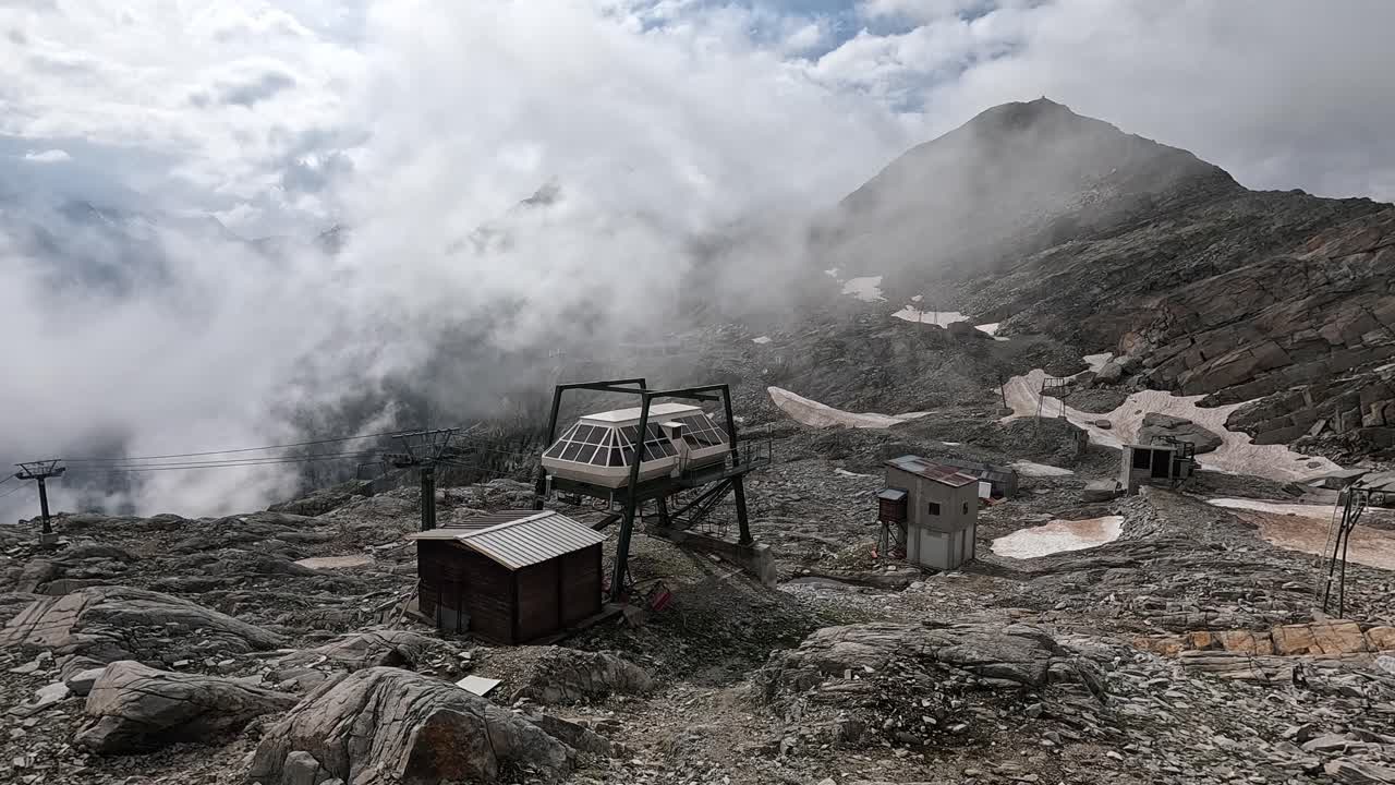 Deserted cable car terminal on rugged alpine slope surrounded by mist and clouds near Monte Rosa, Macugnaga, Italy.