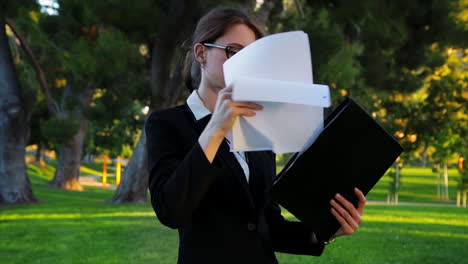 Attractive-caucasian-business-woman-flips-through-paperwork-in-her-folder,-takes-a-look-at-a-document,-checks-her-watch,-and-then-exits