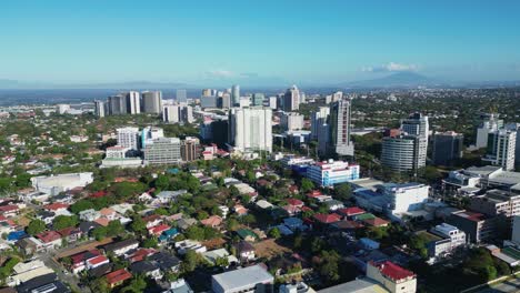 Aerial-flyover-shot-of-scenic-cityscape-of-Alabang,-Las-Piñas,-with-small-barangays-and-tall-modern-buildings-during-daytime