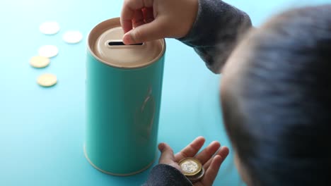 rear view of child girl saving coins in jar