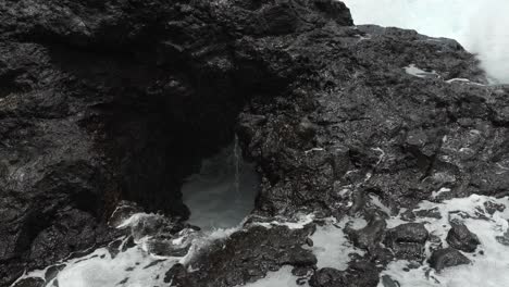 las olas chocan contra las rocas volcánicas de tenerife, creando espuma blanca