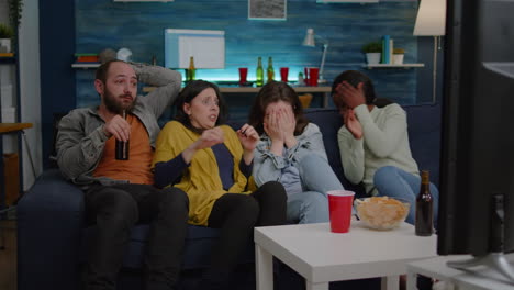 multiracial friends chilling on sofa sitting in front of television