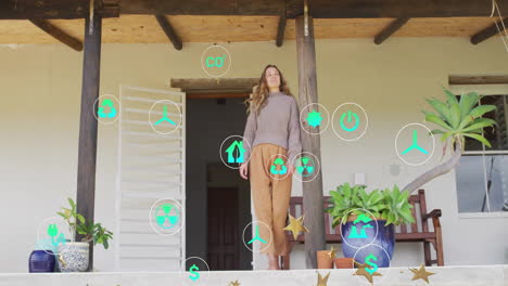 woman standing on veranda presenting renewable energy and finance icons, floating around for design