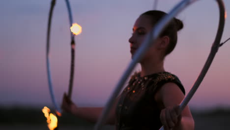 Mujeres-Con-Fuego-Al-Atardecer-En-La-Arena-Bailan-Y-Muestran-Trucos-Contra-El-Hermoso-Cielo-En-Cámara-Lenta