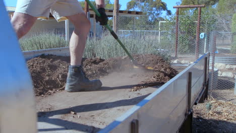 Sweeping-out-dirt,-mulch-or-debris-from-a-ute-or-pickup-truck-using-a-broom-on-a-sunny-day-at-a-farm,-rural-area-or-a-park