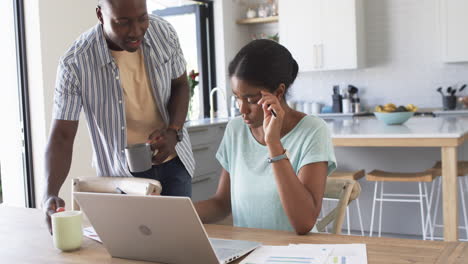 a diverse couple is focused on their finances at home using a laptop