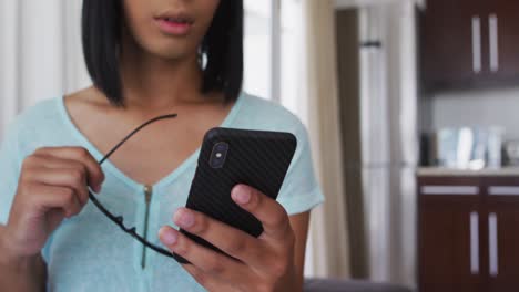 mixed race gender fluid person standing and using smartphone at home