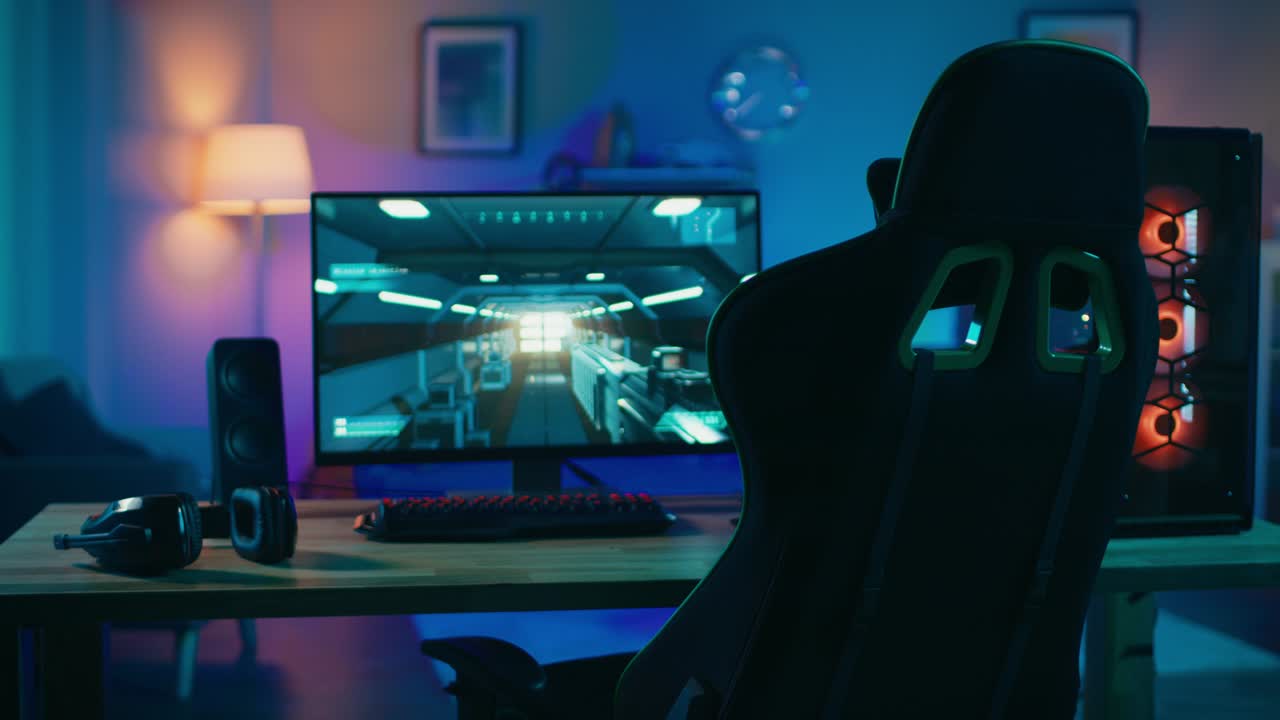 강력한 개인 컴퓨터 게이머 리그와 1인칭 슈팅 게임 화면에 잠시 멈추고 모니터는 집에서 테이블에 서 있습니다. 현대적인 디자인의 아한 방은 따뜻하고 네온 빛으로 조명됩니다.