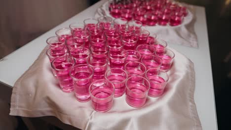 tray of pink shots neatly arranged on a table with a satin cloth