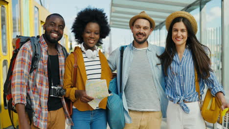 grupo multiétnico de amigos viajeros sonriendo y mirando la cámara en la estación de tren