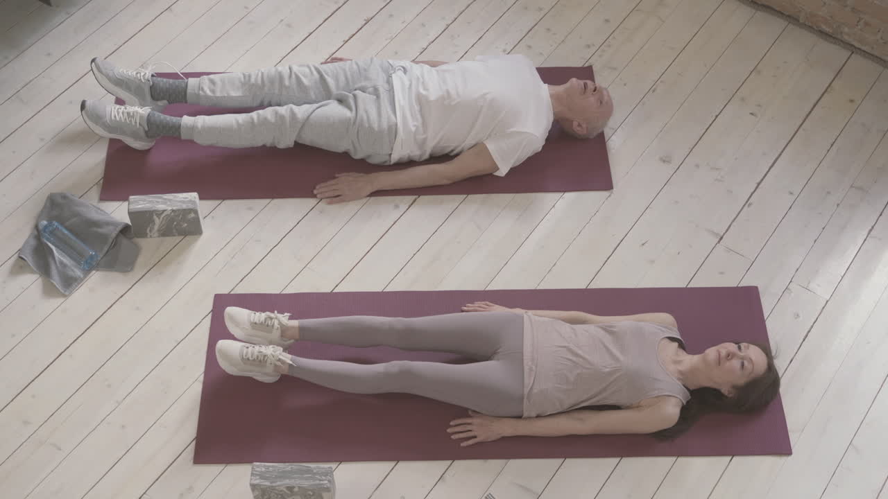 mujeres y hombres viejos haciendo ejercicio en una alfombra de yoga en casa 1