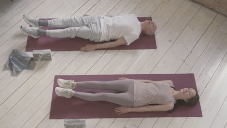 vieille femme et homme faisant de l'exercice sur un tapis de yoga à la maison 1