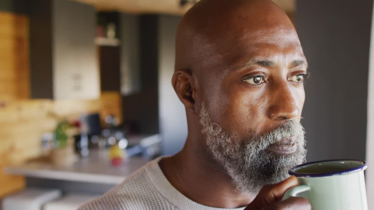 Senior african american man spending time in log cabin and drinking coffee, slow motion