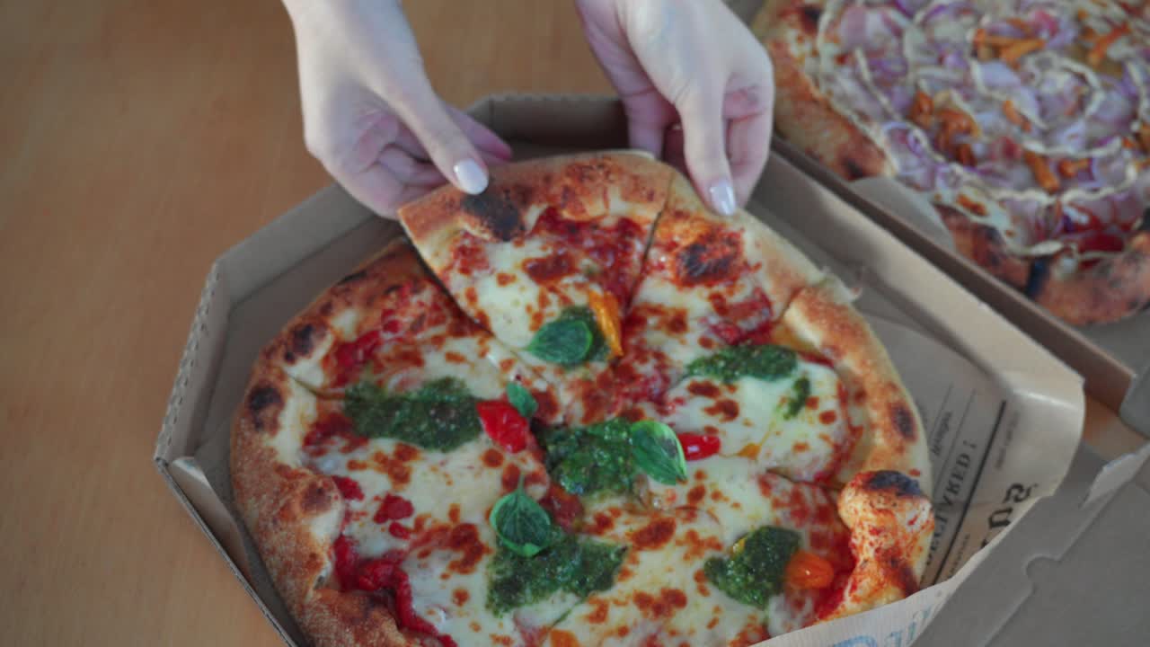 테이블 위에 카드보드 피자 상자에 페스토 소스와 함께 맛있는 나폴리 피자의 조각을 취하는 손의 상단 아래