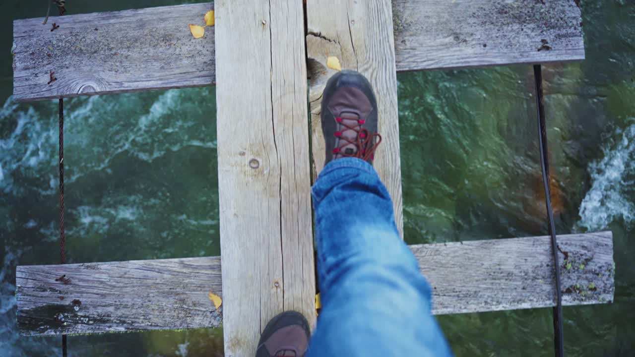 Person crossing wooden bridge over river