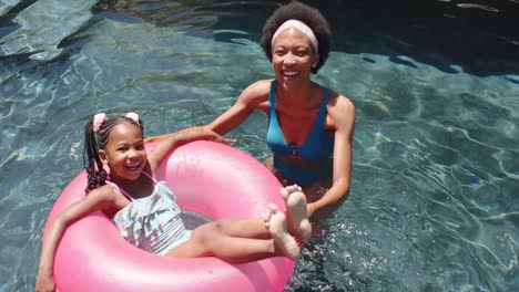 retrato de una feliz madre y hija afroamericanas en la piscina, en cámara lenta
