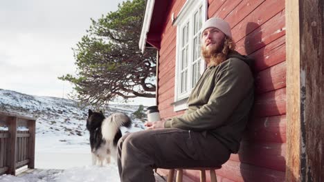 the man is savoring a hot beverage with his dog during winter in bessaker, trondelag county, norway - close up