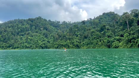 A-person-canoeing-on-Khao-Sok-Lake-with-the-jungle-visible-in-the-background