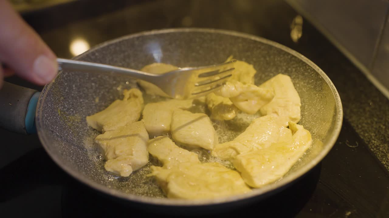 Filmato ravvicinato di un filetto di pollo cucinato e mescolato in una padella