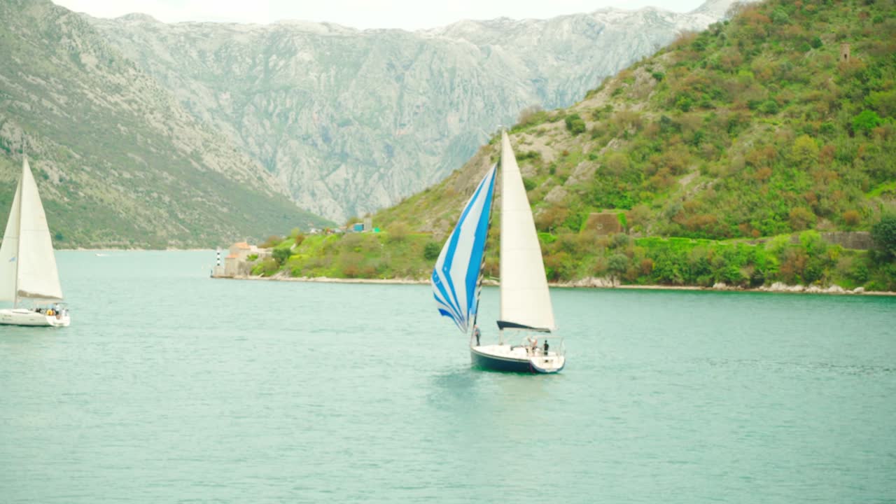 un velero flota en el mar contra el telón de fondo de las montañas en un día de verano
