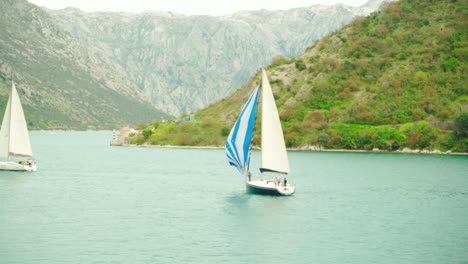 a sailboat floats on the sea against the backdrop of mountains on a summer day