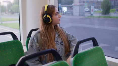 Young-woman-wearing-headphones-listening-music,-funny-relax-dancing-while-traveling-by-bus-to-city