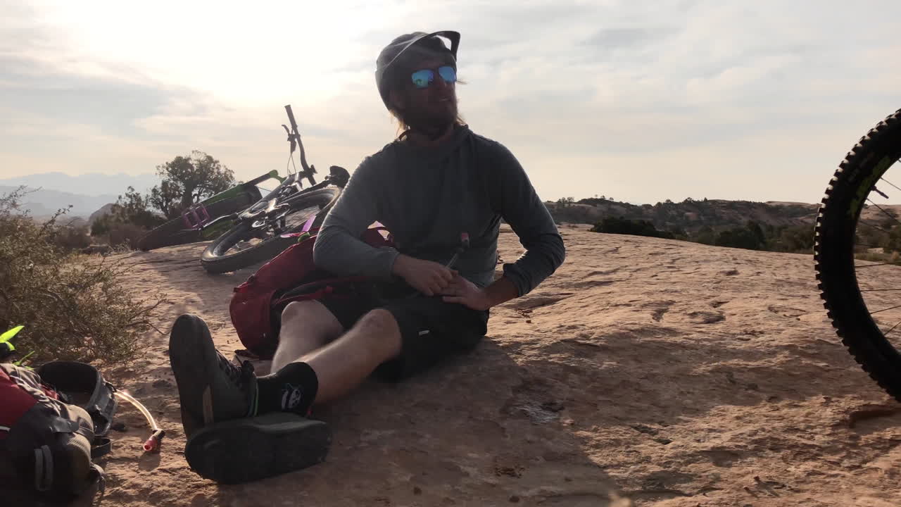 En atletisk mountainbikecyklist som dricker ur sin vätskeblåsa