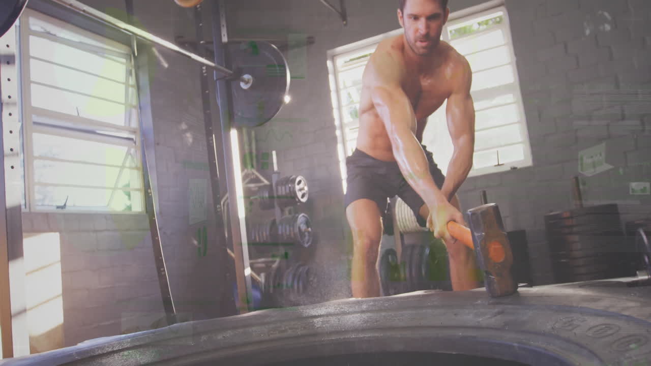 Male fitness enthusiast swinging sledgehammer at tractor tire in gym, showing animated weight icons