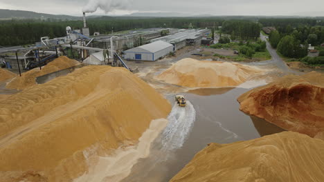 High-angle-view-of-wheel-dozer-distributing-sawdust-at-lumber-mill,-Norway