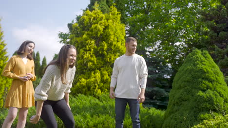 kaukasische junge frau, die an einem sonnigen tag einen petanque-ball im park wirft, dann high fives mit ihrer freundin