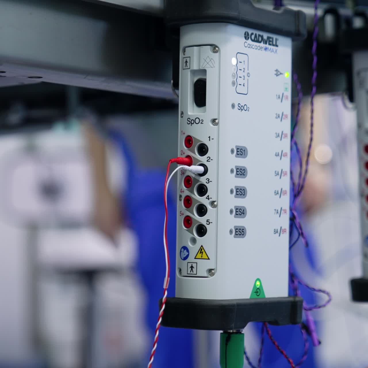 Plugging the little wires into the slots of equipment. Preparation for neuromonitoring of patient. Close up