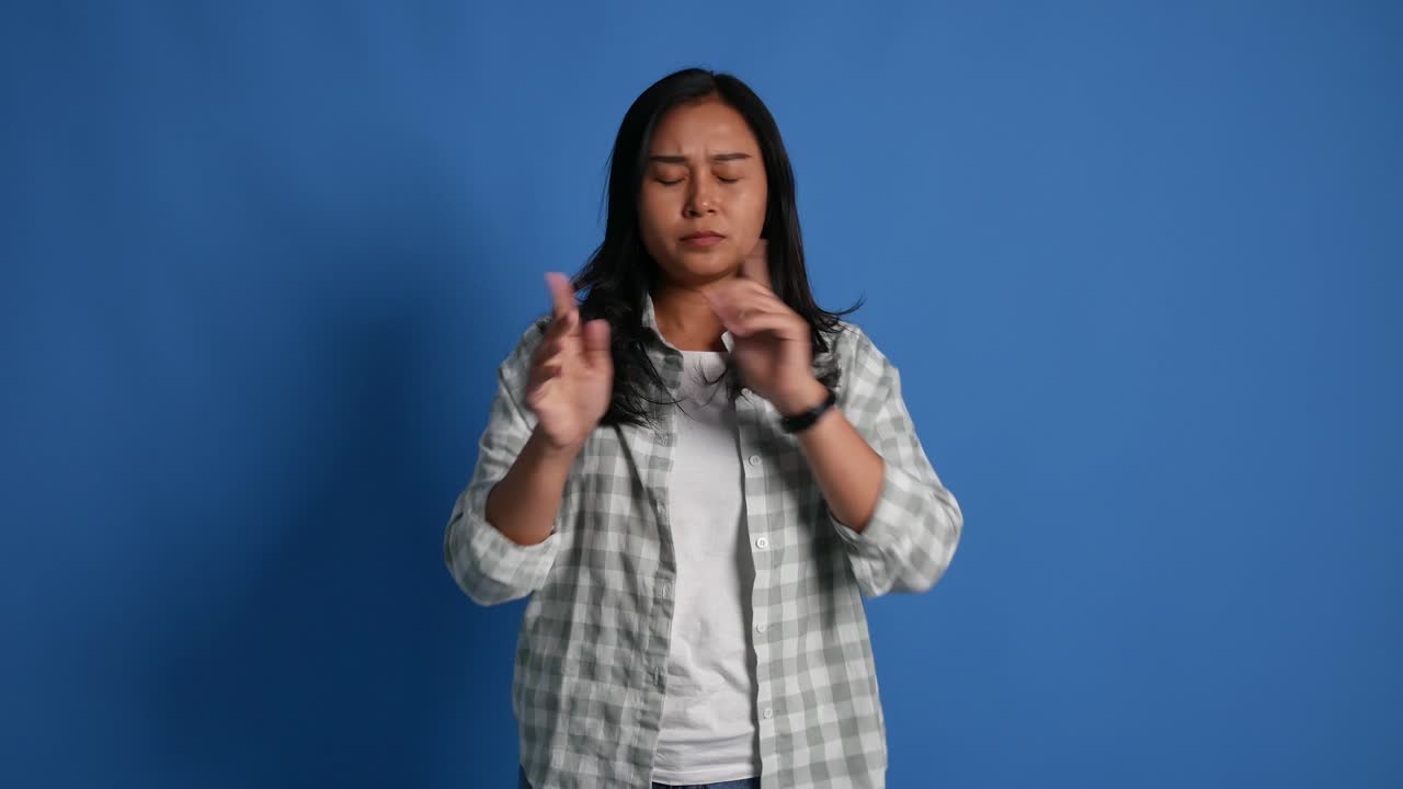 Displeased young asian woman isolated on blue background in studio. People lifestyle concept. Pointing fingers on herself ask say who me no thanks i do not need it