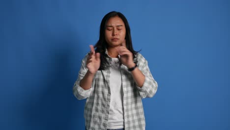 displeased young asian woman isolated on blue background in studio. people lifestyle concept. pointing fingers on herself ask say who me no thanks i do not need it