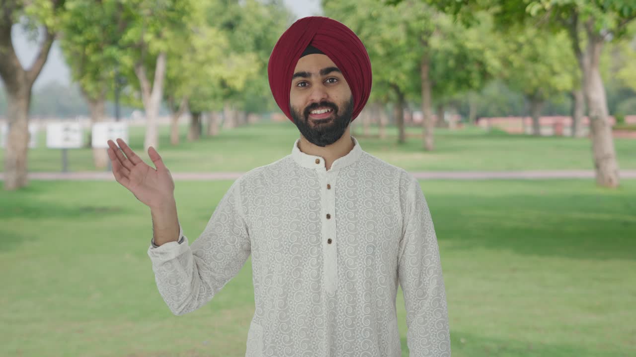 Uomo indiano Sikh felice che saluta nel parco