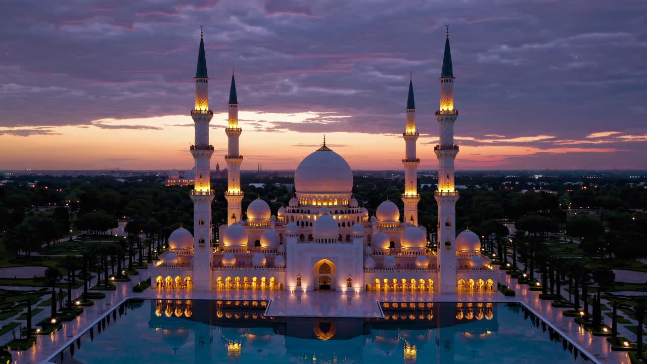 Un video aereo cattura una grande moschea al tramonto, mostrando le sue cupole e i suoi minareti illuminati